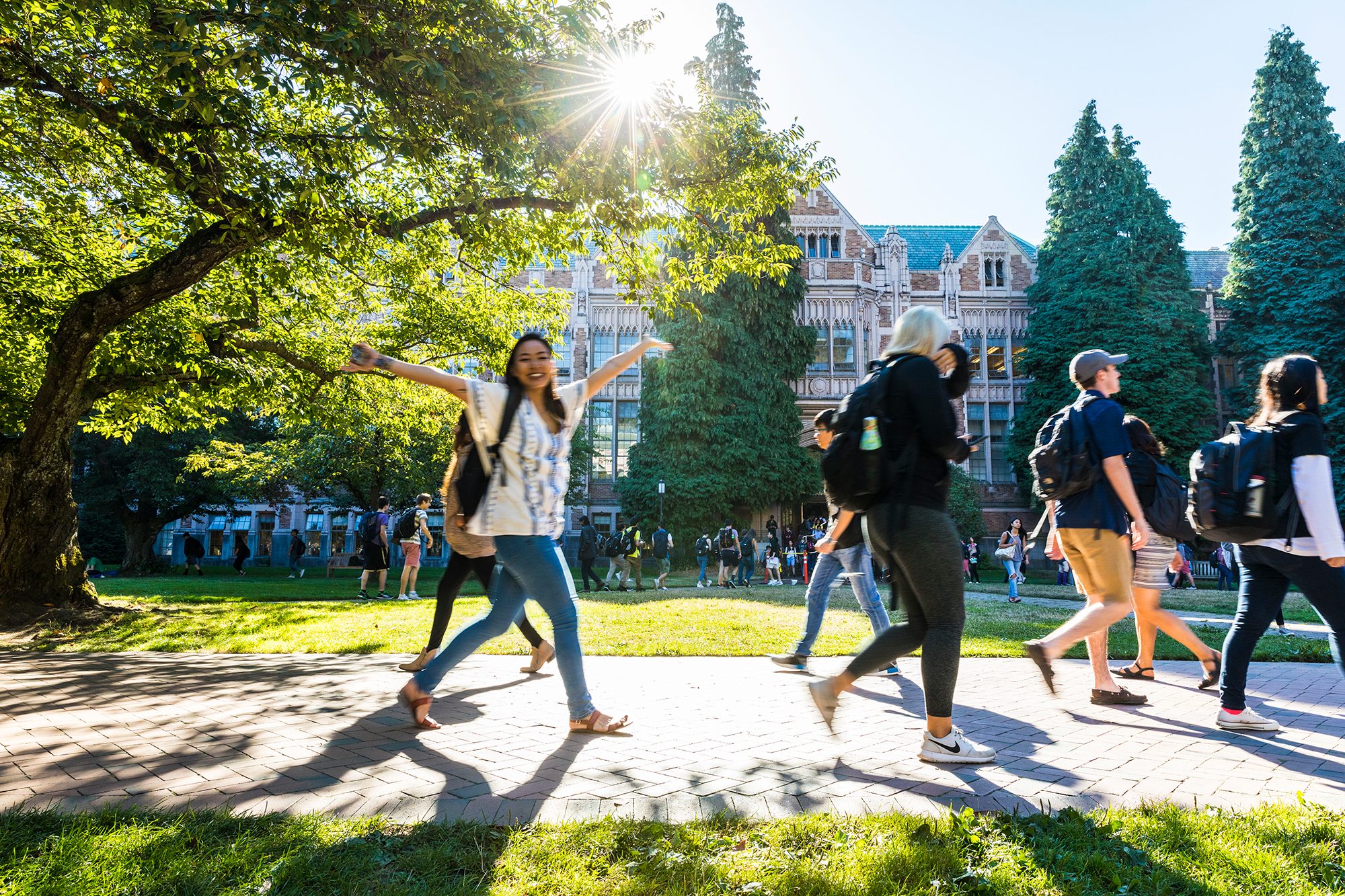 a happy student with arms raised walking on campus